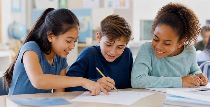 Three elementary and middle school students solve a worksheet together.